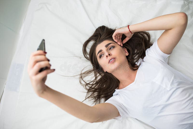 Frau auf ihrem Bettnehmen selfy lizenzfreie stockfotografie Frau auf ihrem Bettnehmen selfy lizenzfreie stockfotografie