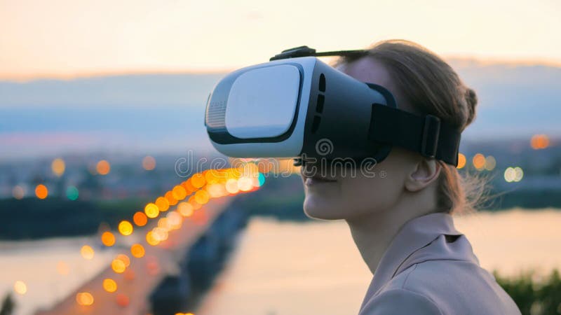 Frau benutzt Gl?ser der virtuellen Realit?t in der Stadt nach Sonnenuntergang lizenzfreie stockfotografie Frau benutzt Gl?ser der virtuellen Realit?t in der Stadt nach Sonnenuntergang lizenzfreie stockfotografie
