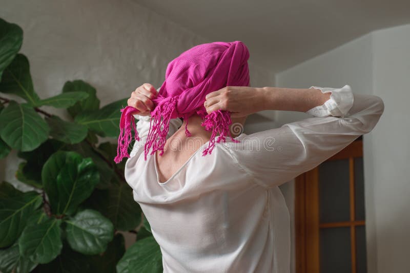 Frau bindet ein Halstuch auf ihrem Kopf