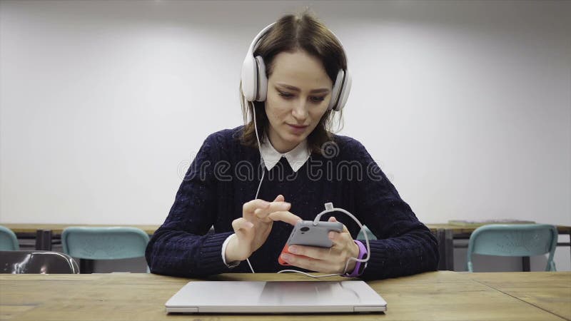 Frau in den Kopfhörern schlägt ein intelligentes Telefon leicht stock video footage Frau in den Kopfhörern schlägt ein intelligentes Telefon leicht stock video footage