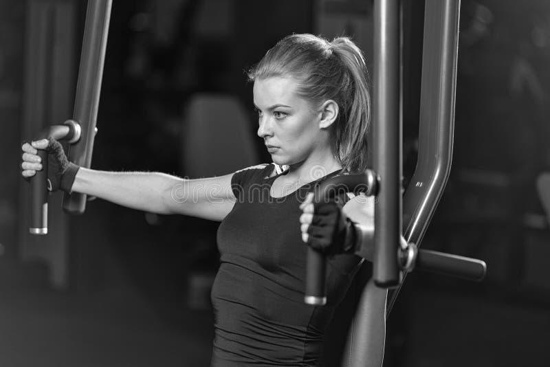 Frau an der Sportturnhalle, die Armübungen auf einer Maschine tut stockfoto Frau an der Sportturnhalle, die Armübungen auf einer Maschine tut stockfoto