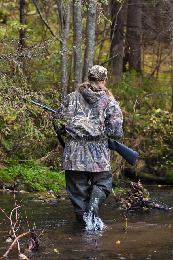 Frau in der Tarnung, die kleinen Fluss auf der Jagd kreuzt stockfoto Frau in der Tarnung, die kleinen Fluss auf der Jagd kreuzt stockfoto