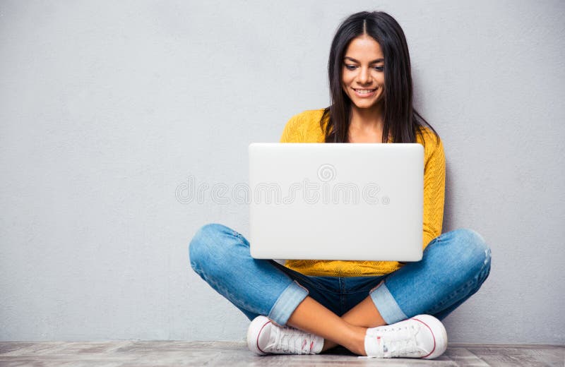 Frau, die auf dem Boden sitzt und Laptop verwendet stockfotografie