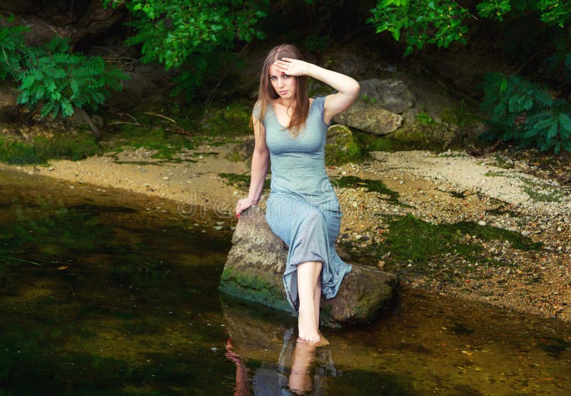 Frau, Die Auf Dem Felsen in Einem Teich Sitzt Stockfoto Bild von