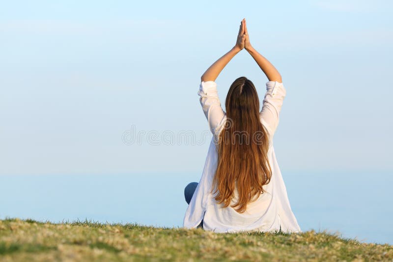 Frau, die auf dem Gras Yoga praktiziert und den Horizont sieht