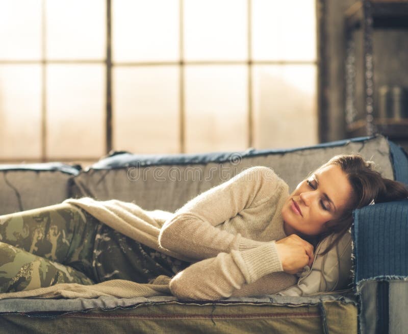 Frau, die auf einem Sofa in einem Stadtdachboden Nickerchen macht lizenzfreies stockbild Frau, die auf einem Sofa in einem Stadtdachboden Nickerchen macht lizenzfreies stockbild