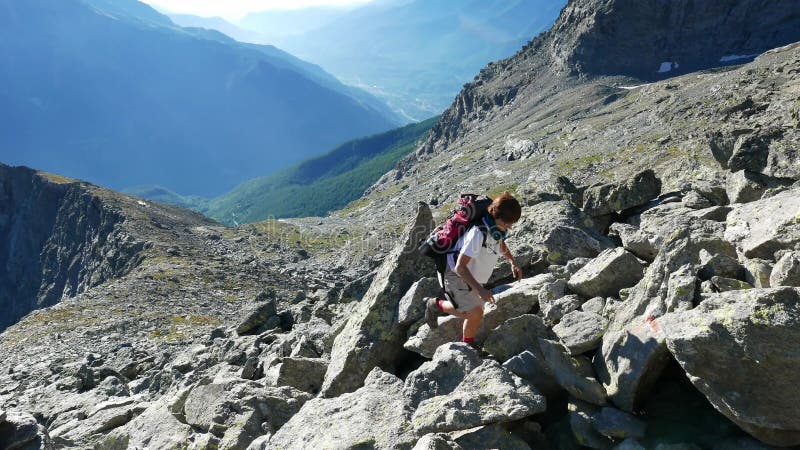 Frau, die auf Klippe der großen Höhe felsiger Gebirgsklettert Sommerabenteuer auf den italienischen französischen Alpen