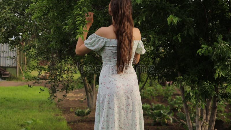 Frau, die Baumzweige im Garten berührt