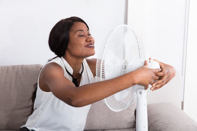 Frau, die Brise mit elektrischem Ventilator genießt lizenzfreie stockfotos Frau, die Brise mit elektrischem Ventilator genießt lizenzfreie stockfotos
