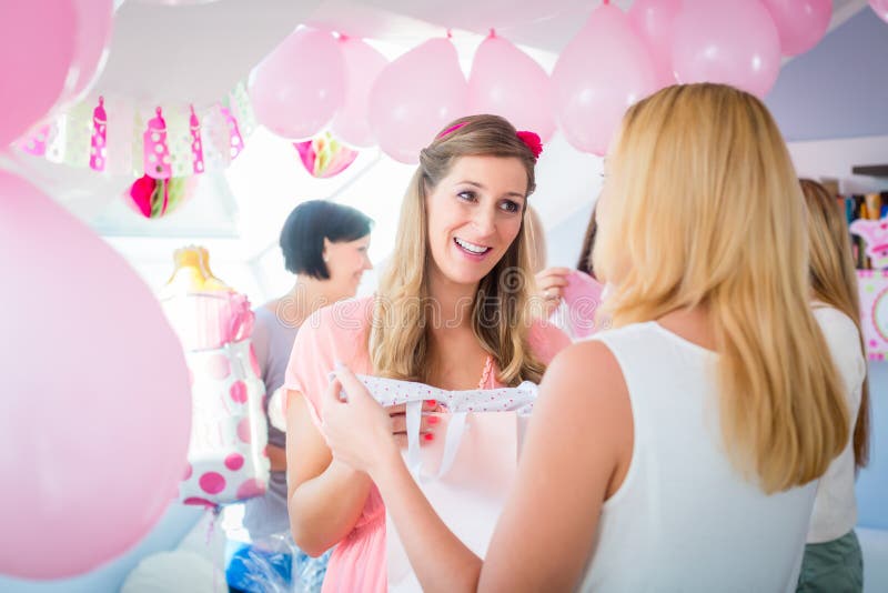 Frau, die dem schwangeren Freund auf Babyparty Geschenk gibt lizenzfreies stockbild Frau, die dem schwangeren Freund auf Babyparty Geschenk gibt lizenzfreies stockbild