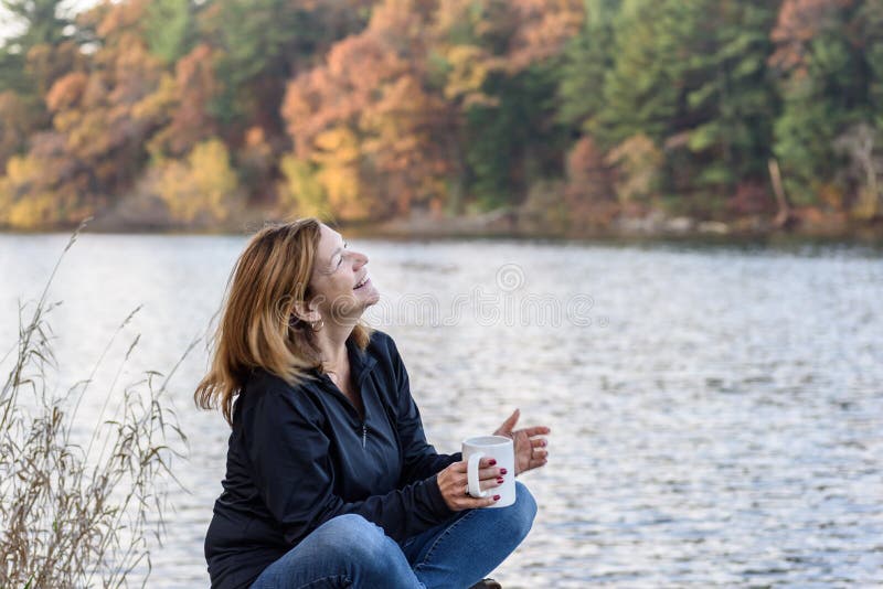 Frau, die den Tasse Kaffee lacht entlang Seeseite mit colorf hält lizenzfreie stockfotos Frau, die den Tasse Kaffee lacht entlang Seeseite mit colorf hält lizenzfreie stockfotos