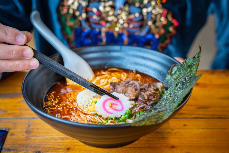 Frau, die eine japanische Nudelsuppe der würzigen Ramen in einer schwarzen Farberamenschüssel isst stockfoto Frau, die eine japanische Nudelsuppe der würzigen Ramen in einer schwarzen Farberamenschüssel isst stockfoto