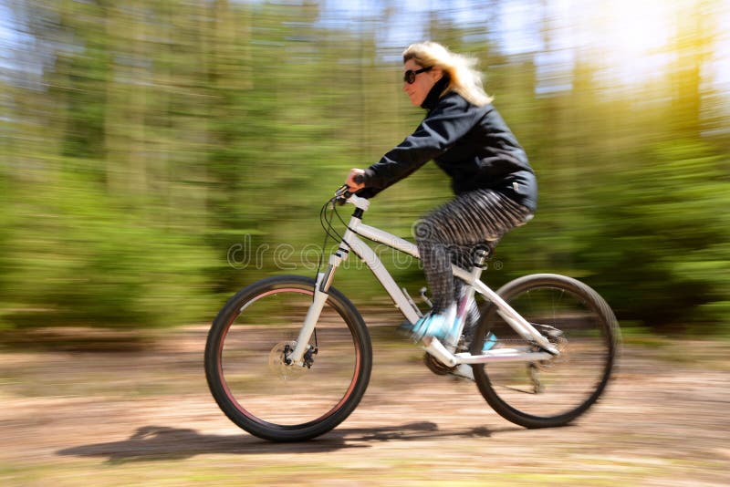 Frau, die eine Mountainbike auf einen Waldweg reitet lizenzfreie stockfotografie Frau, die eine Mountainbike auf einen Waldweg reitet lizenzfreie stockfotografie