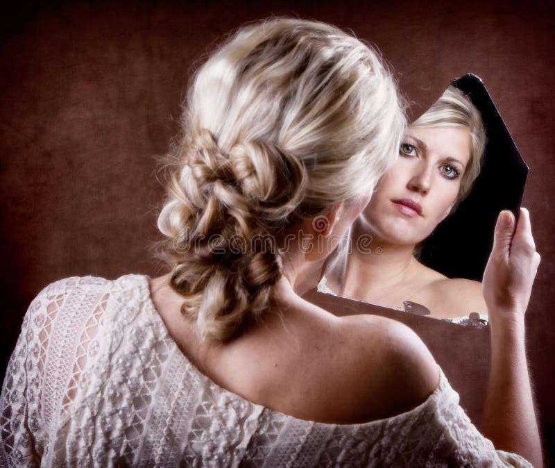 Woman looking into a broken mirror with back of head showing. Woman looking into a broken mirror with back of head showing