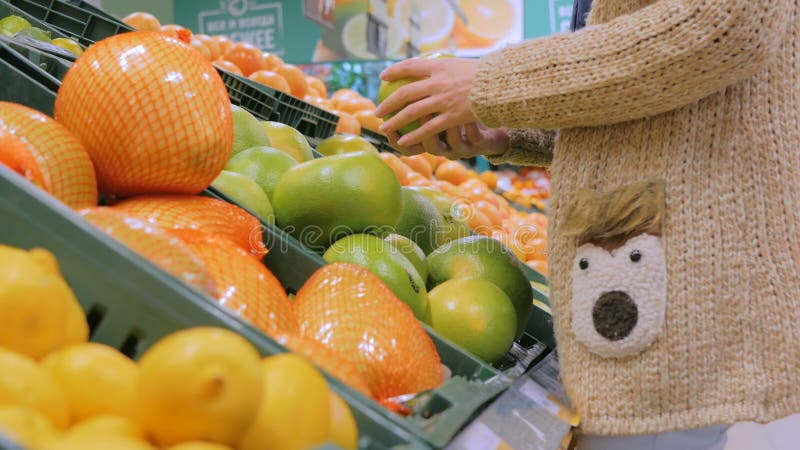 Frau, die frische exotische Zitrusfrüchte am Gemischtwarenladen kauft