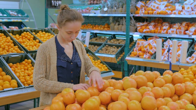 Frau, die frische Pampelmusen am Gemischtwarenladen kauft