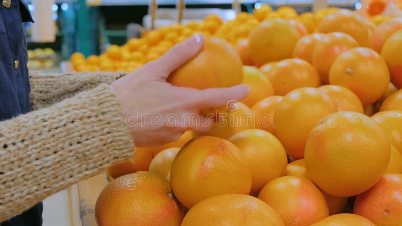 Frau, die frische Pampelmusen am Gemischtwarenladen kauft