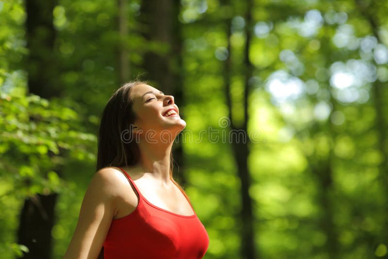 Frau, die Frischluft im Wald atmet