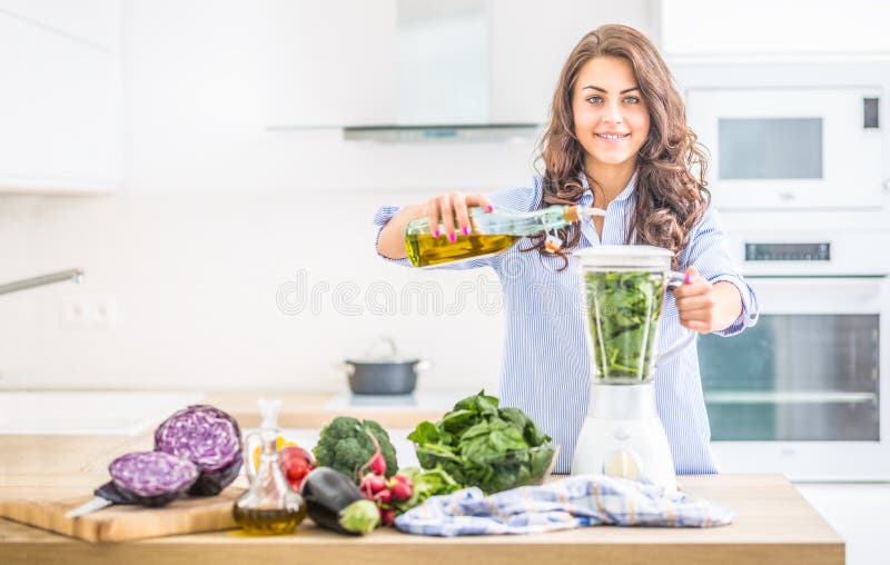 Frau, die Gemüsesuppe oder Smoothies mit Mischmaschine in ihrer Küche macht Junge glückliche Frau, die gesunde Nahrung oder Geträ stockbild