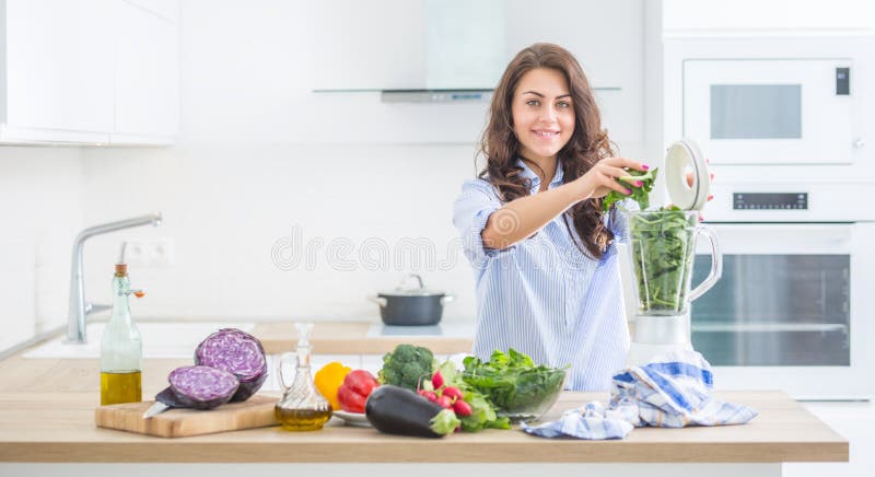 Frau, die Gemüsesuppe oder Smoothies mit Mischmaschine in ihrer Küche macht Junge glückliche Frau, die gesundes Getränk mit Spina stockbilder
