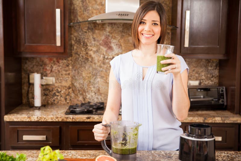 Portrait of a young brunette drinking some green healthy juice as part of her detox diet. Portrait of a young brunette drinking some green healthy juice as part of her detox diet