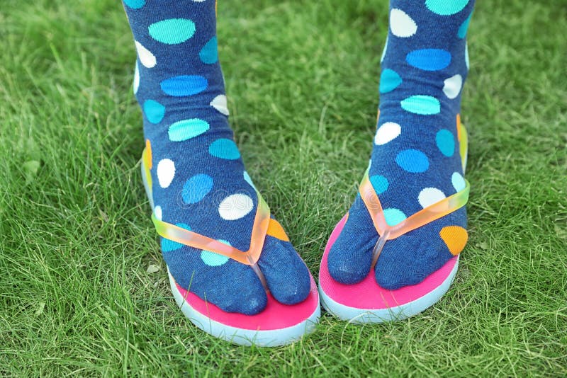 Woman wearing bright socks with flip-flops standing on grass. Woman wearing bright socks with flip-flops standing on grass