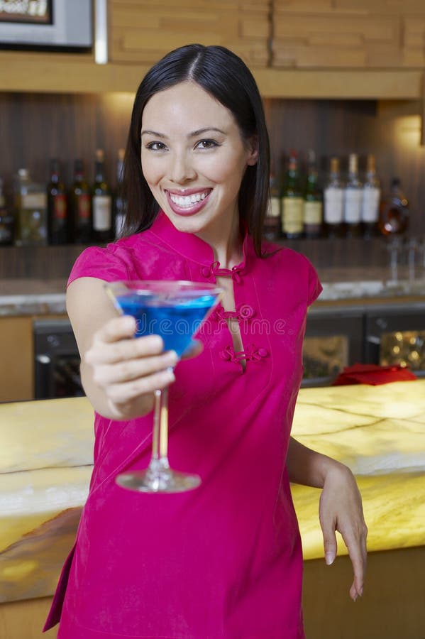 Frau, die heraus blauen Martini hält stockfotografie Frau, die heraus blauen Martini hält stockfotografie