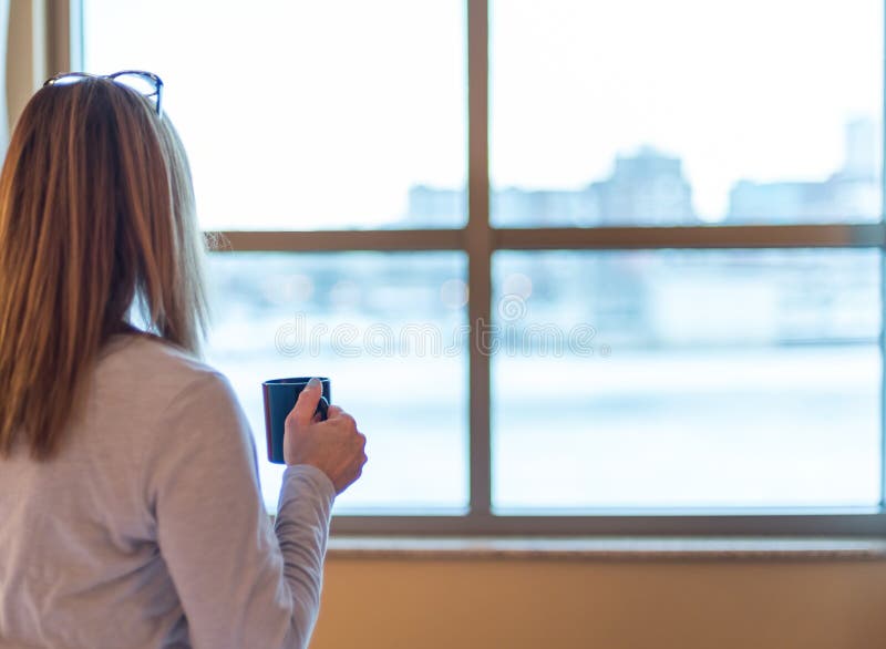 Frau, die heraus Hotelfenster mit Kaffee aufwacht und in der Hand schaut stockfotos Frau, die heraus Hotelfenster mit Kaffee aufwacht und in der Hand schaut stockfotos