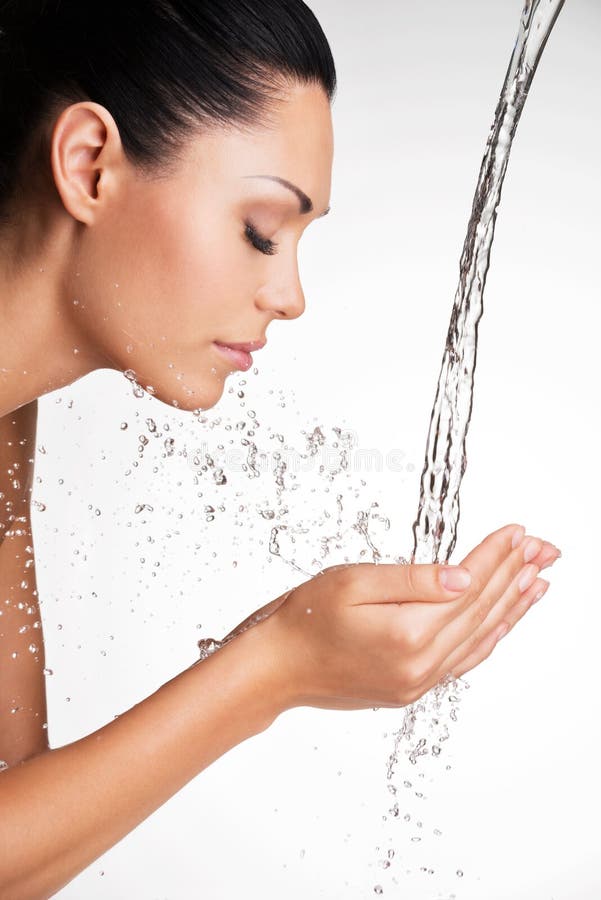 Frau, die ihr sauberes Gesicht mit Wasser wäscht