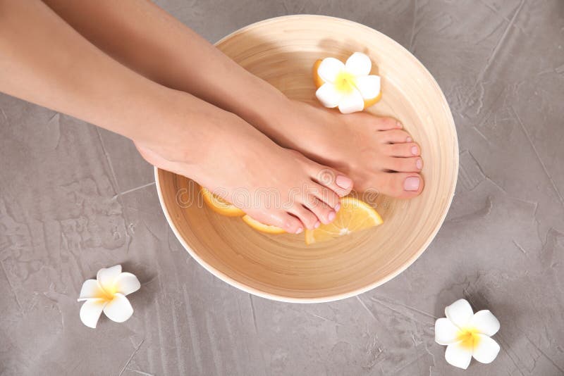 Frau, die ihre Füße in der Schüssel mit Wasser, orange Scheiben und Blume auf grauem Hintergrund, Draufsicht tränkt lizenzfreies stockfoto Frau, die ihre Füße in der Schüssel mit Wasser, orange Scheiben und Blume auf grauem Hintergrund, Draufsicht tränkt lizenzfreies stockfoto