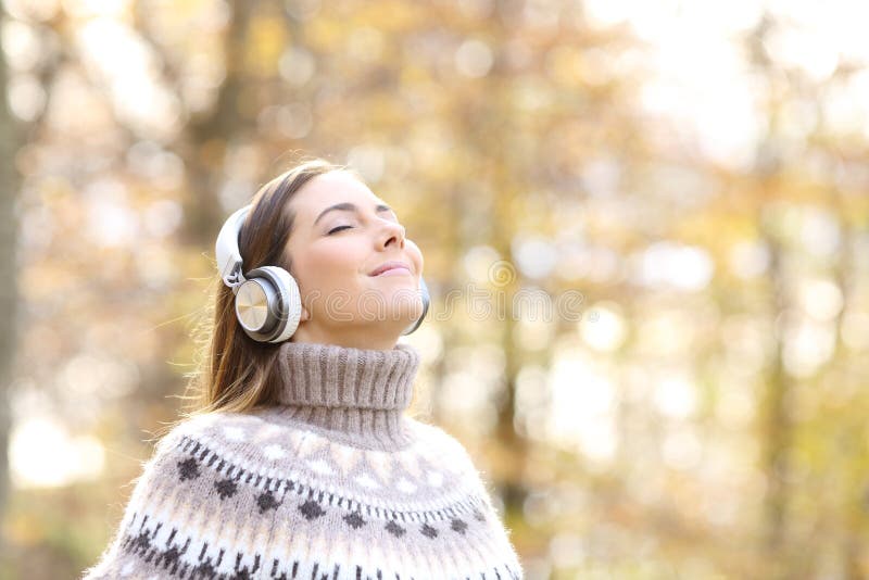Frau, die im Herbst Musik hört und atmet