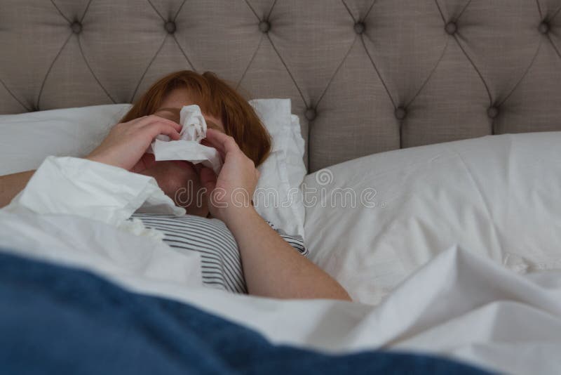 Frau, die im Seidenpapier im Schlafzimmer niest lizenzfreies stockbild Frau, die im Seidenpapier im Schlafzimmer niest lizenzfreies stockbild