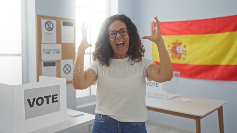 Frau, die im Wahlzimmer mit spanischer Flagge feiert und Aufregung und Glück in einem Wahlkollegium zeigt stockfoto