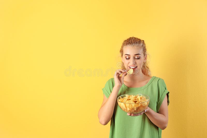 Frau, die Kartoffelchips auf Farbhintergrund isst stockfotografie Frau, die Kartoffelchips auf Farbhintergrund isst stockfotografie