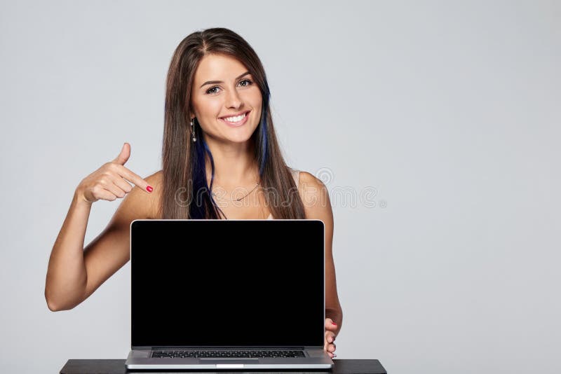 Happy woman showing blank black laptop computer screen, looking at camera pointing finger at monitor. Happy woman showing blank black laptop computer screen, looking at camera pointing finger at monitor