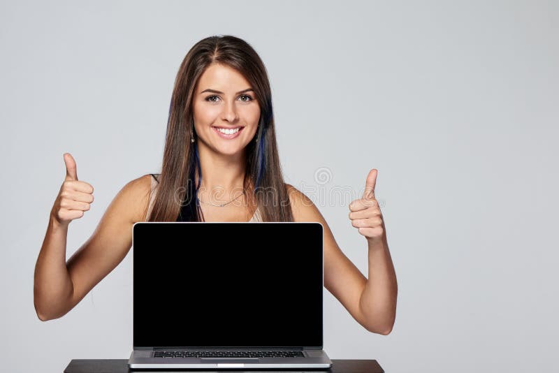 Happy woman showing blank black laptop computer screen, looking at camera and giving double thumbs up. Happy woman showing blank black laptop computer screen, looking at camera and giving double thumbs up