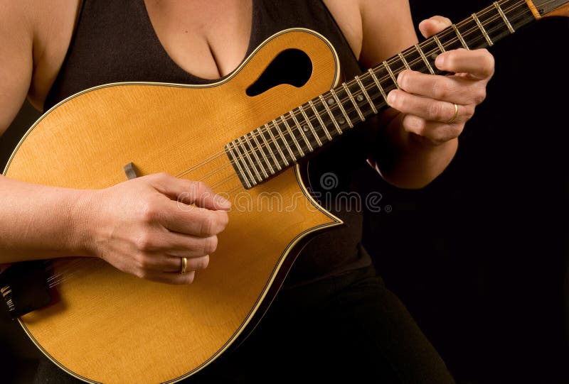 Close up of woman playing the mandolin, against black. Close up of woman playing the mandolin, against black.