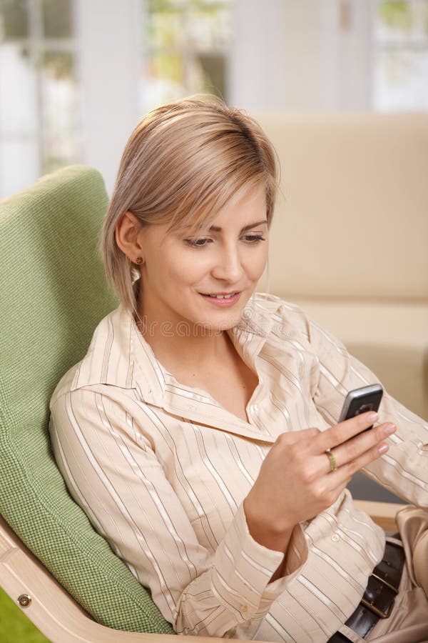 Frau, die Mobiltelefon im Lehnsessel verwendet stockbilder Frau, die Mobiltelefon im Lehnsessel verwendet stockbilder