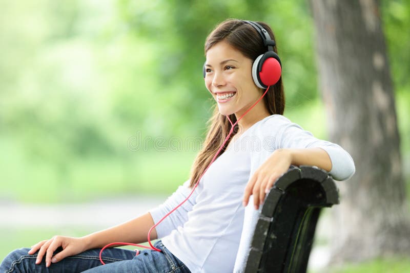 Frau, die Musik im Park hört lizenzfreies stockbild Frau, die Musik im Park hört lizenzfreies stockbild