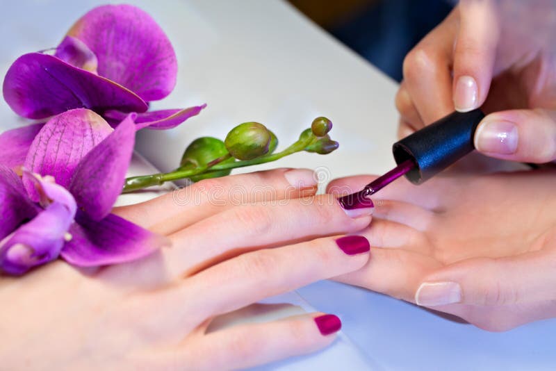 Frau, die Nagellack an den Fingernägeln aufträgt stockfotografie Frau, die Nagellack an den Fingernägeln aufträgt stockfotografie