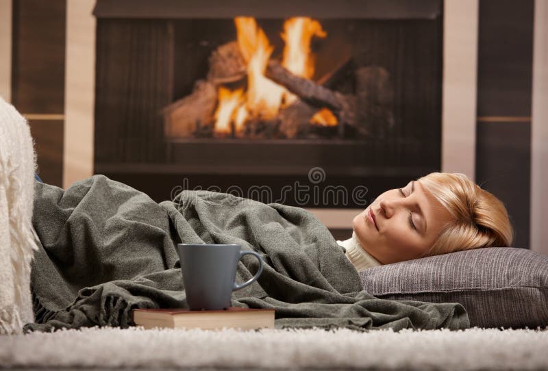 Woman sleeping at home lying on floor in front of a fire place,. Woman sleeping at home lying on floor in front of a fire place,