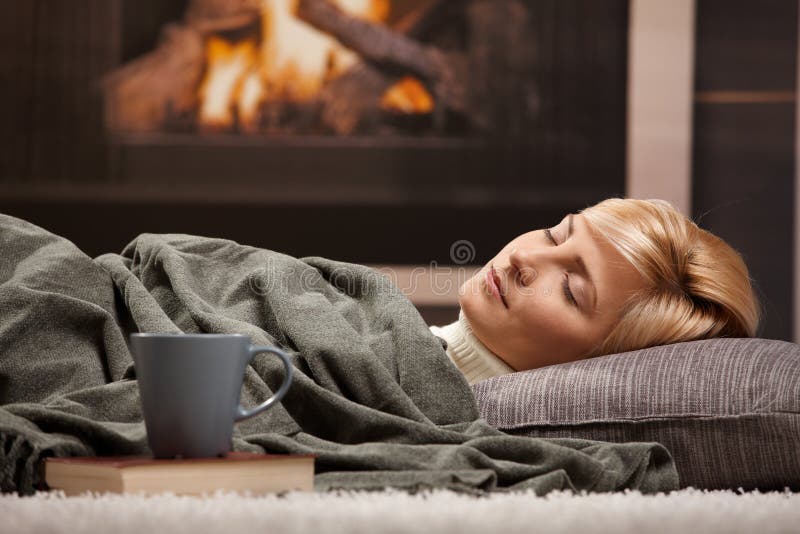 Woman sleeping at home lying on floor in front of a fire place,. Woman sleeping at home lying on floor in front of a fire place,
