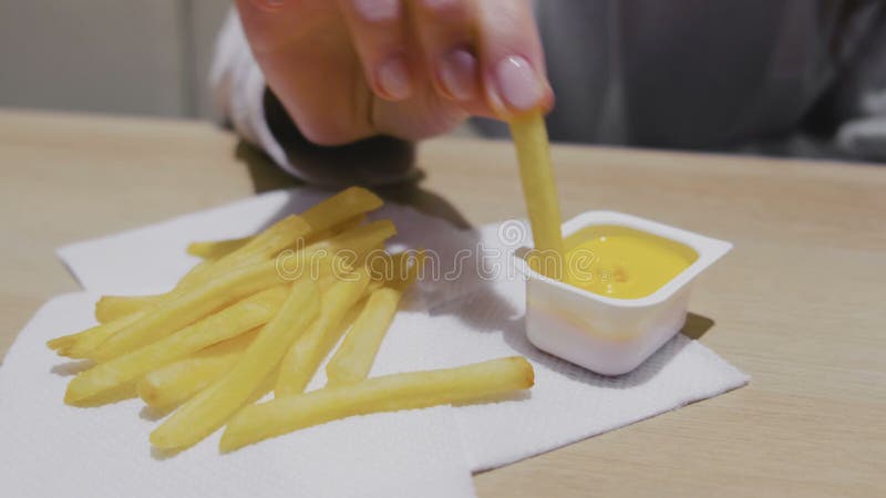 Frau, die Pommes-Frites mit Käsesoße im Café isst Nahaufnahmehände