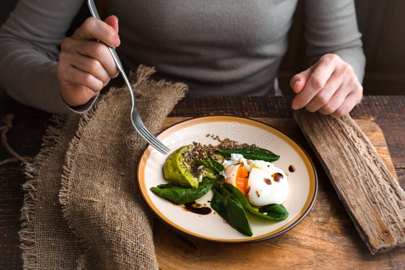 Woman eating poached egg with avocado cream and spinach horizontal. Woman eating poached egg with avocado cream and spinach horizontal