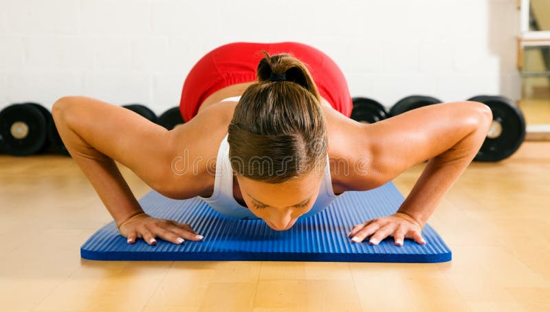 Frau, die Pushups in der Gymnastik tut Frau, die Pushups in der Gymnastik tut
