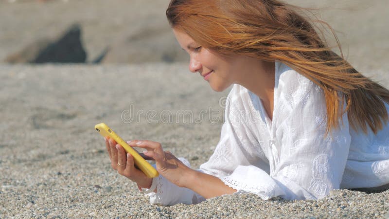 Frau, die Smartphone am Strand verwendet