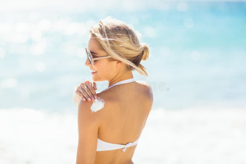 Frau, die Sonnencreme auf ihrer Schulter aufträgt stockfotografie Frau, die Sonnencreme auf ihrer Schulter aufträgt stockfotografie