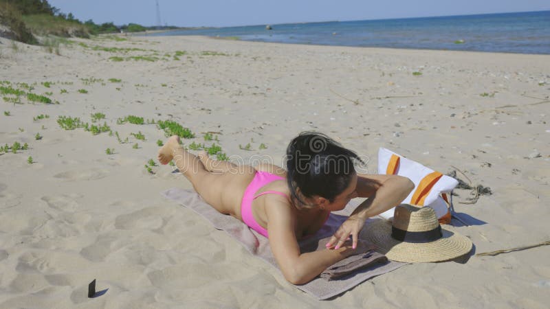 Frau, die am Strand unter einer hellen Sonne liegt