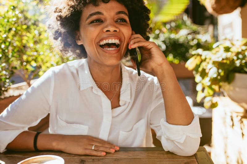 Frau, die am Telefon an einem Café lächelt und spricht lizenzfreies stockfoto Frau, die am Telefon an einem Café lächelt und spricht lizenzfreies stockfoto