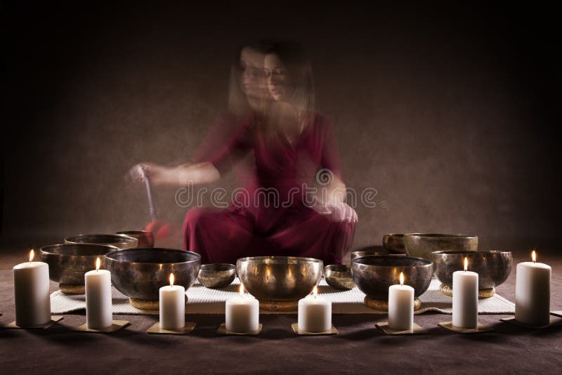 Blur motion of a woman playing a Tibetan bowls, focus on a singing bowls. Blur motion of a woman playing a Tibetan bowls, focus on a singing bowls